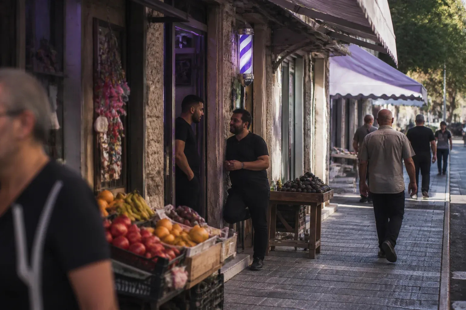 שורת חנויות קטנות ברחוב שכונתי ובעלי החנויות משוחחים בפתחים