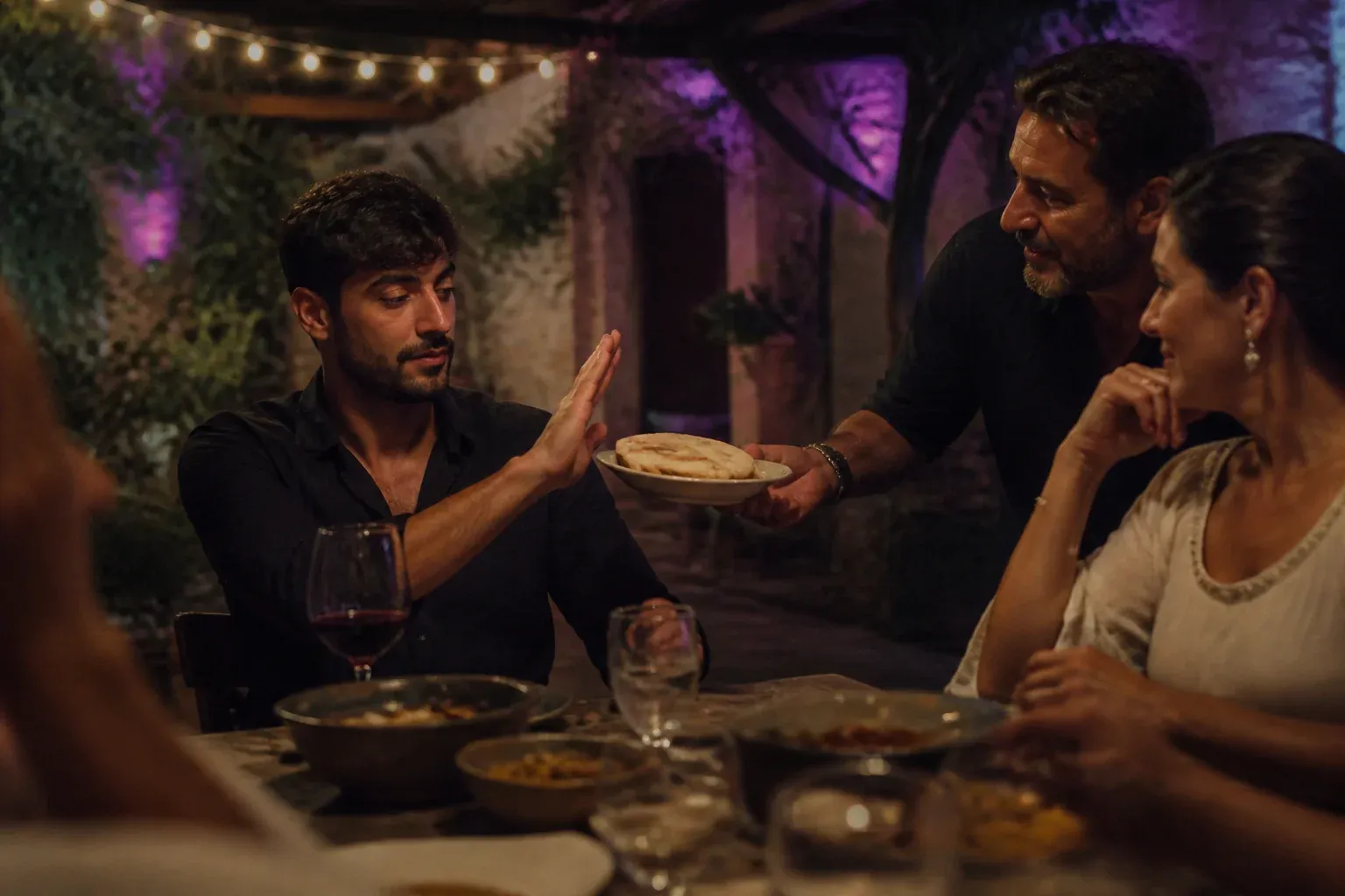 אורח בשולחן חצר משפחתי מרים יד ומסרב בנימוס למנה שמציע המארח